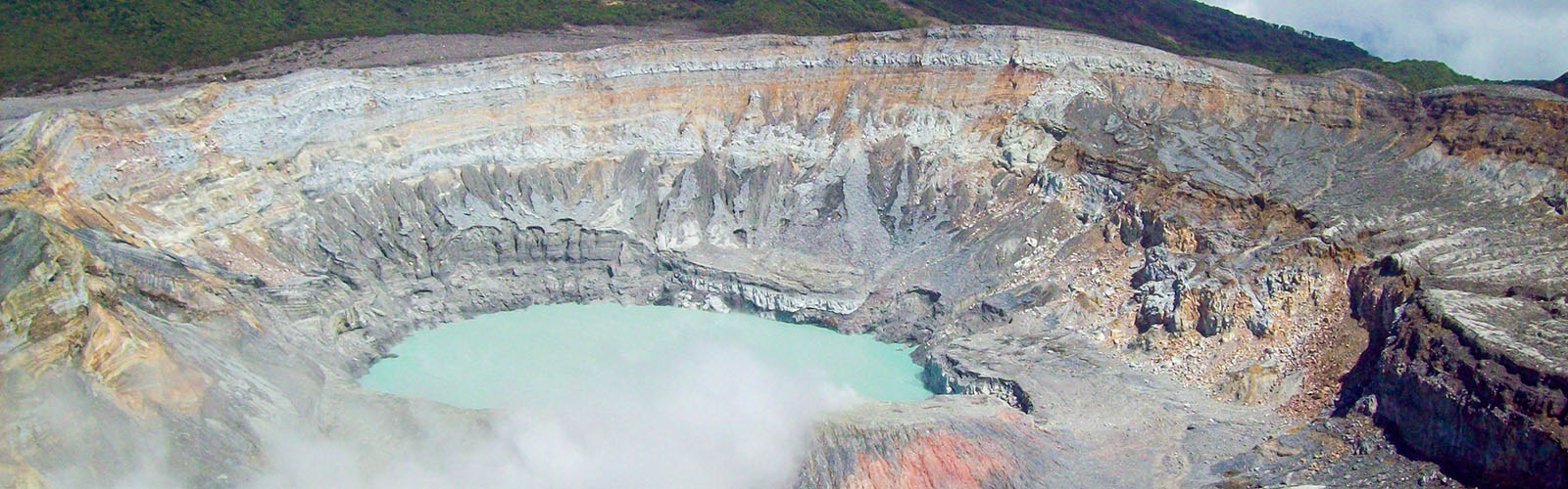 Drone shot of an oasis in the middle of a crater. Fog is surrounding the crater in the background.